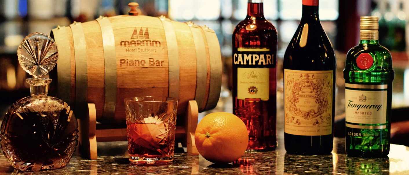 An elegant bar with a wooden barrel, various bottles of spirits and a glass of drink on a shiny counter., &copy; Maritim Hotels