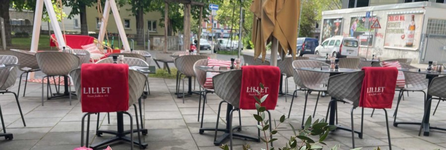 Outdoor seating area with modern chairs and tables, red Lillet blankets and flowers in the foreground. Trees and buildings can be seen in the background., © SMG Outdoor seating area with modern chairs and tables, red Lillet blankets and flowers in the foreground. Trees and buildings can be seen in the background., © SMG