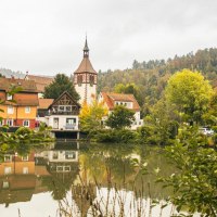 Town lake in Bad Liebenzell with colorful houses and church tower, surrounded by autumnal trees. Reflection in the water, framed by green bushes., © SMG, Sarah Schmid