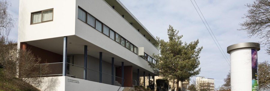 Modern building with a white façade and large windows, surrounded by trees and a billboard., © SMG Stuttgart Marketing GmbH - Sarah Schmid