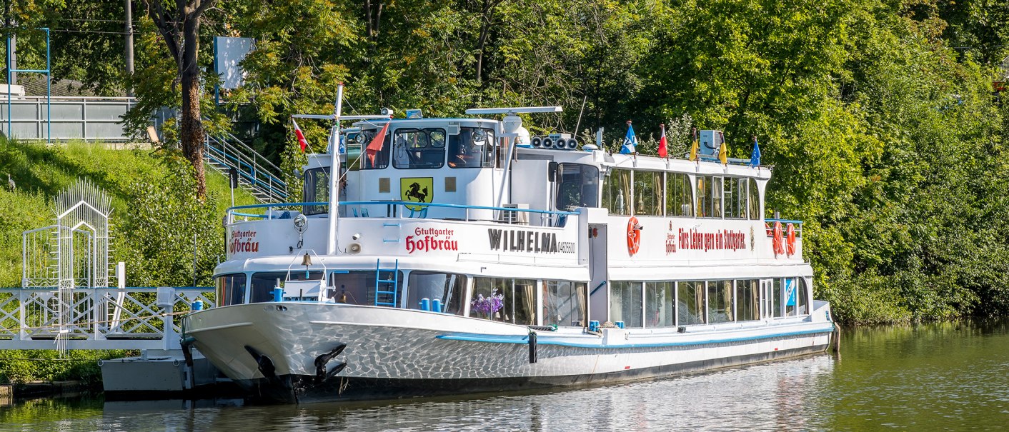 The passenger ship MS Wilhelma is anchored on a green riverbank, surrounded by trees., © all copyrights are reserved by maks richter