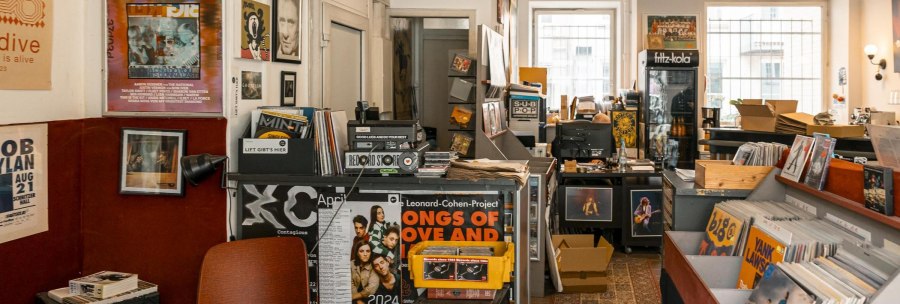 A cozy record store with vinyls, posters and music magazines. In the background, a fridge with drinks and a desk with a computer., © SMG, Sarah Schmid