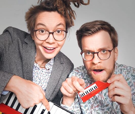 Zwei Personen mit Brillen halten rote Musikinstrumente, ein Keyboard und eine kleine Melodica, und schauen fröhlich in die Kamera., © Rosenau Kultur e.V. Zwei Personen mit Brillen halten rote Musikinstrumente, ein Keyboard und eine kleine Melodica, und schauen fröhlich in die Kamera., © Rosenau Kultur e.V.