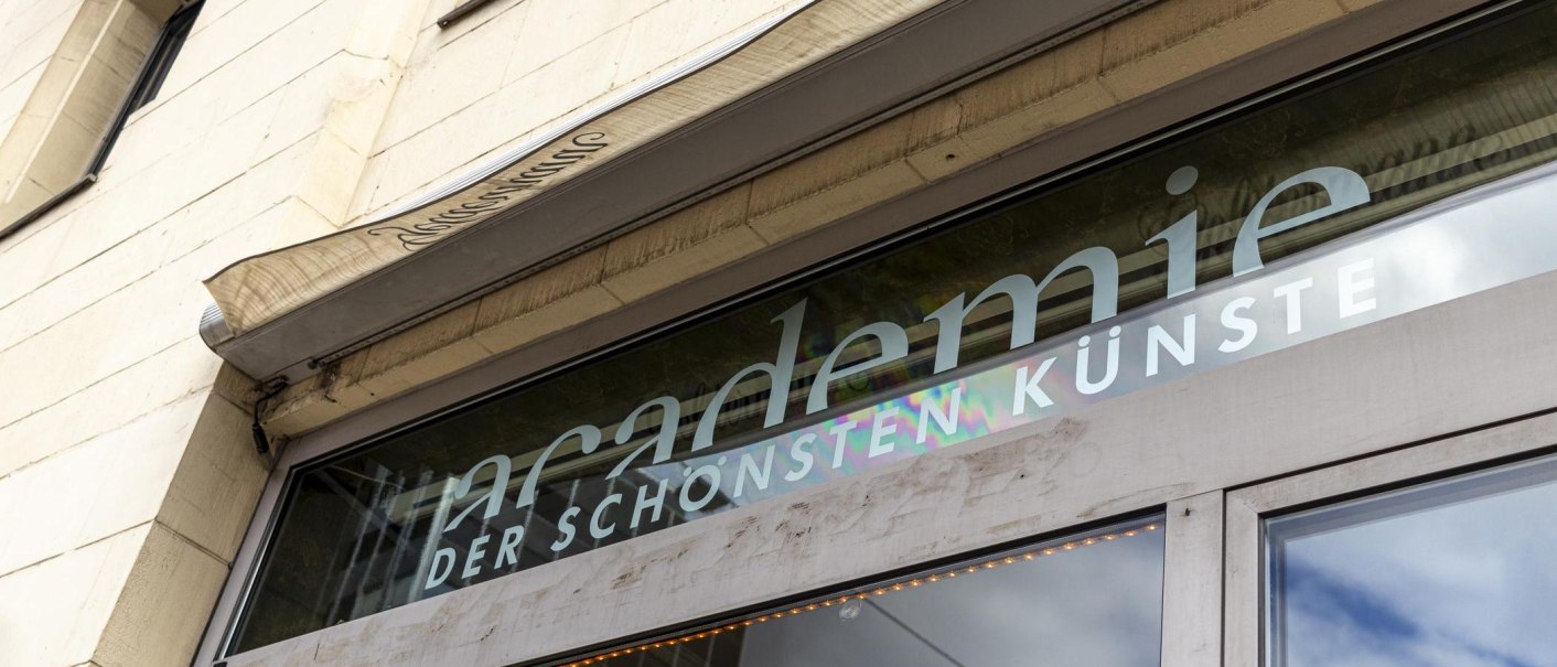 Nahaufnahme des Eingangs der Akademie der schönsten Künste mit Schriftzug auf einer Glasfront., © SMG, Sarah Schmid Nahaufnahme des Eingangs der Akademie der schönsten Künste mit Schriftzug auf einer Glasfront., © SMG, Sarah Schmid