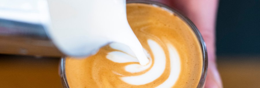 Nahaufnahme eines Cappuccinos, in den Milch gegossen wird, um ein Latte Art-Muster zu erzeugen., &copy; Sven Weber