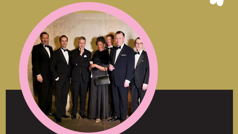 Eine Gruppe von sieben Personen in eleganter Abendgarderobe posiert vor einer Wand. Sie tragen Anz&uuml;ge und ein Abendkleid, wirken fr&ouml;hlich und stilvoll., &copy; Renitenztheater Stuttgart e.V.