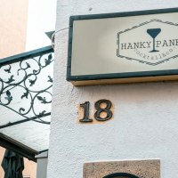 Ein Schild mit der Aufschrift 'Hanky Panky Cocktail & co' h&auml;ngt an einer Hauswand mit der Nummer 18. Eine Laterne und ein dekoratives Vordach sind sichtbar., &copy; Stuttgart-Marketing GmbH, Sarah Schmid