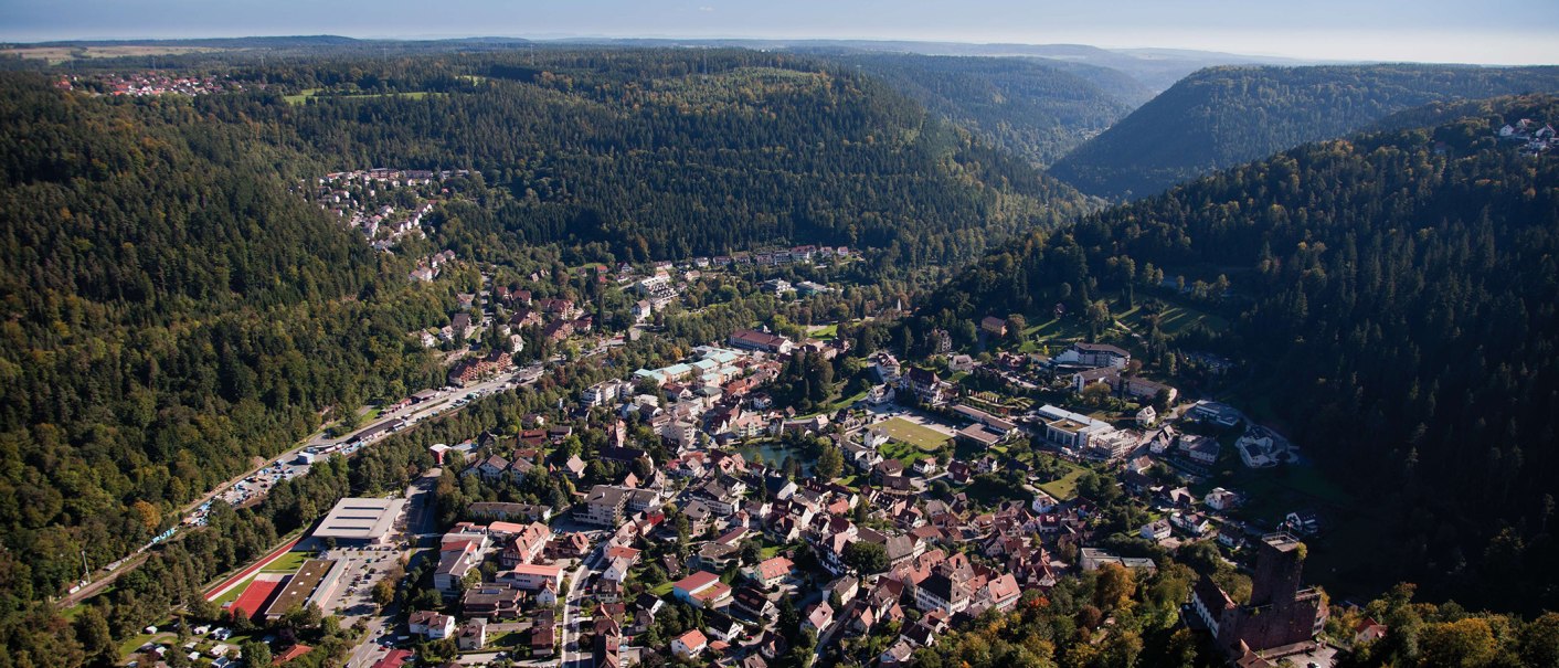Aerial view of Bad Liebenzell in the Black Forest, surrounded by dense forests and hills. The town lies in a valley with many buildings and streets., © © Stuttgart-Marketing GmbH (SMG) Aerial view of Bad Liebenzell in the Black Forest, surrounded by dense forests and hills. The town lies in a valley with many buildings and streets., © © Stuttgart-Marketing GmbH (SMG)