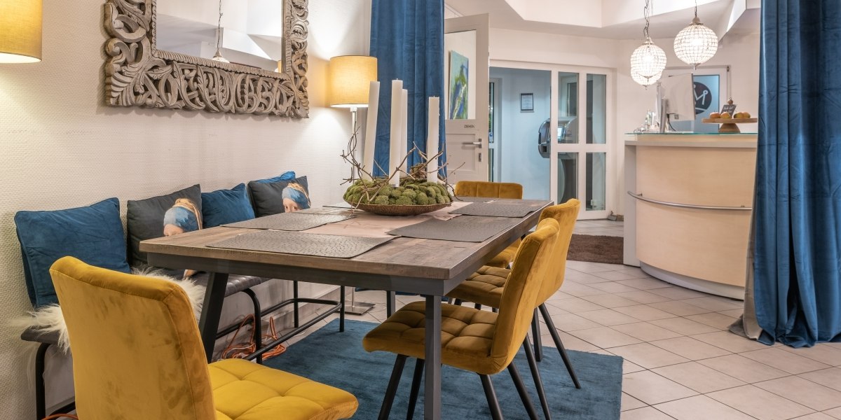 Gemütliche Lounge mit Esstisch, gelben Stühlen, blauem Teppich und dekorativem Spiegel. Im Hintergrund eine Empfangstheke und moderne Beleuchtung., © Hotel Princess Gemütliche Lounge mit Esstisch, gelben Stühlen, blauem Teppich und dekorativem Spiegel. Im Hintergrund eine Empfangstheke und moderne Beleuchtung., © Hotel Princess