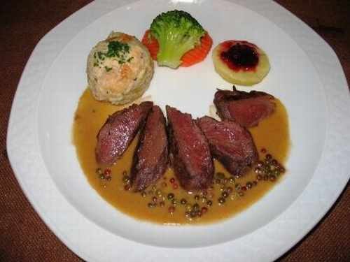 Wildschweinrücken in Pfefferrahmsoße mit Semmelknödel, Brokkoli, Karotten und Preiselbeeren auf einem Teller angerichtet., © Ulli Kellenbenz