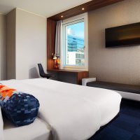 Ein modernes Hotelzimmer mit einem gro&szlig;en Bett, einem Schreibtisch am Fenster und einem Flachbildfernseher an der Wand., &copy; Aloft Stuttgart