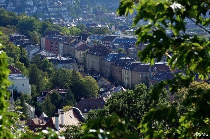Stadtansicht mit historischen Gebäuden und viel Grün, umrahmt von Bäumen. Im Hintergrund sind Hügel zu sehen., © Stuttgart Marketing GmbH