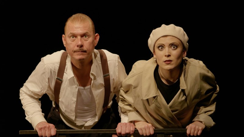 Zwei Personen in Theaterkostümen schauen gespannt nach vorne. Der Mann trägt Hosenträger, die Frau einen Hut. Der Hintergrund ist schwarz., © Theater tri-bühne, Anton Avdieiev Zwei Personen in Theaterkostümen schauen gespannt nach vorne. Der Mann trägt Hosenträger, die Frau einen Hut. Der Hintergrund ist schwarz., © Theater tri-bühne, Anton Avdieiev