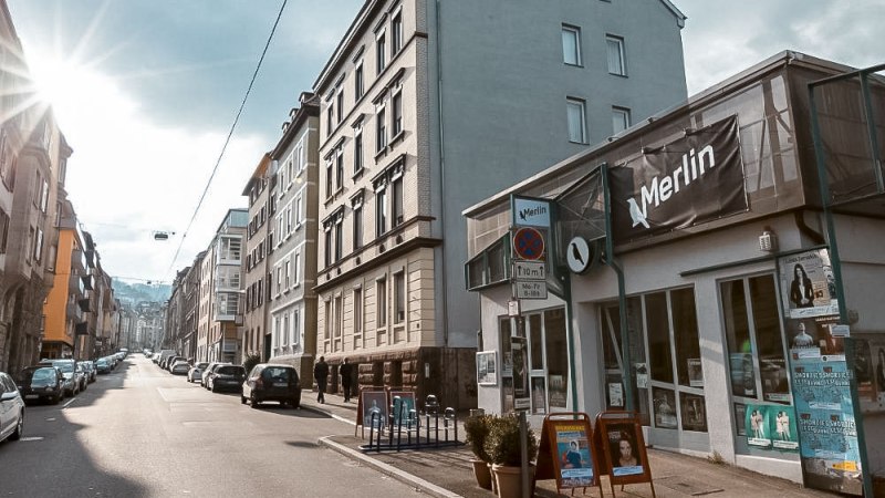 Street scene in Stuttgart with the cultural center Merlin e.V. on the right. The sun is shining, cars are parked along the street., © Merlin, Stuttgart Street scene in Stuttgart with the cultural center Merlin e.V. on the right. The sun is shining, cars are parked along the street., © Merlin, Stuttgart