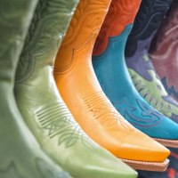 A row of colorful cowboy boots in various colors and patterns, including green, orange and blue, on display in a store., &copy; DBoots by Boots, Stuttgart