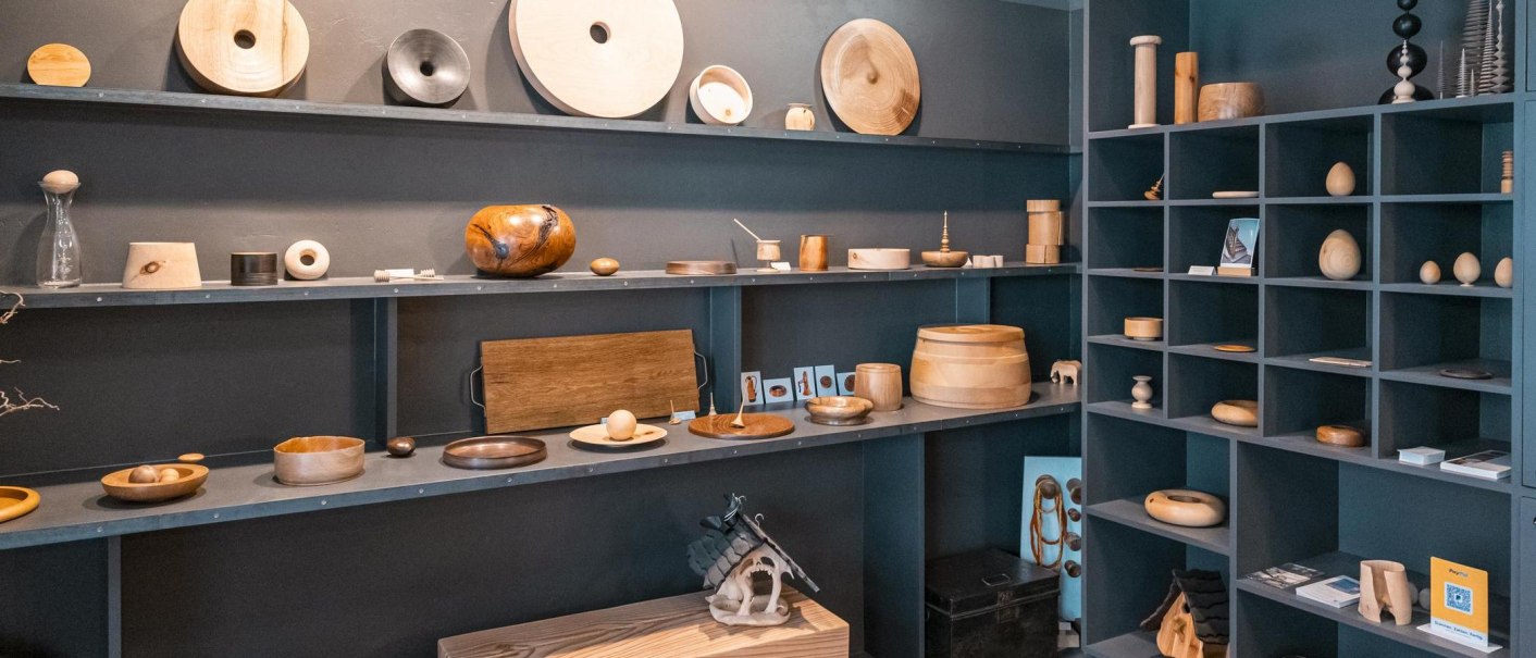 Ein Regal mit verschiedenen Holzobjekten und Dekorationen in einem Raum mit blauen Wänden. Die Objekte sind kunstvoll arrangiert., © SMG, Sarah Schmid