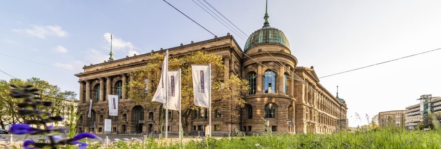 The Haus der Wirtschaft in Stuttgart with its magnificent façade and dome, surrounded by flags and green vegetation., © © Stuttgart-Marketing GmbH, Werner Dieterich