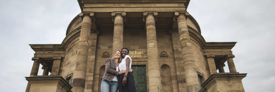 Zwei Personen umarmen sich l&auml;chelnd vor der imposanten Fassade der Grabkapelle Stuttgart mit ihren S&auml;ulen., &copy; Stuttgart-Marketing GmbH, wpsteinheisser