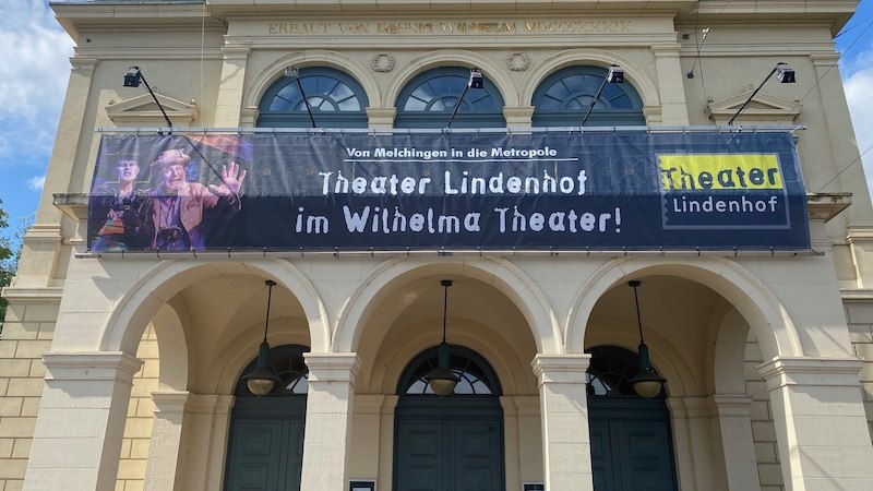 Fassade des Wilhelma Theaters mit einem großen Banner des Theater Lindenhof. Der Schriftzug lautet: 'Von Melchingen in die Metropole'., © Wilhelma Theater Fassade des Wilhelma Theaters mit einem großen Banner des Theater Lindenhof. Der Schriftzug lautet: 'Von Melchingen in die Metropole'., © Wilhelma Theater