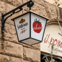Ein Schild mit Schöfferhofer-Logo und Tomatenmotiv hängt an einer Steinwand vor dem Restaurant 'il pomodoro'., © SMG, Sarah Schmid