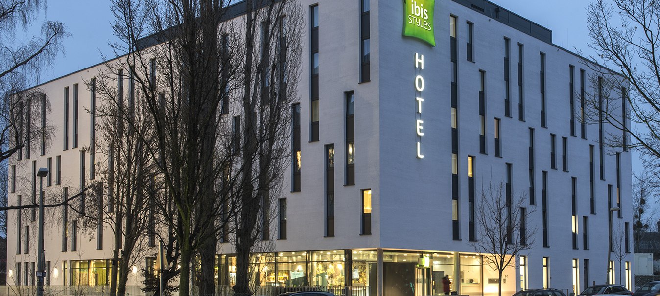 Modernes Hotelgebäude des ibis Styles Stuttgart Vaihingen bei Dämmerung, beleuchtet mit Autos auf der Straße davor., © ibis Styles Stuttgart Vaihingen Modernes Hotelgebäude des ibis Styles Stuttgart Vaihingen bei Dämmerung, beleuchtet mit Autos auf der Straße davor., © ibis Styles Stuttgart Vaihingen