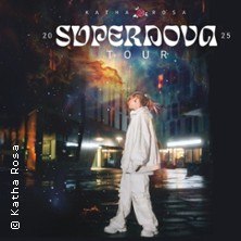 Person in weißem Outfit steht vor einem kosmischen Hintergrund mit dem Schriftzug 'Supernova Tour 2025'., © links im Bild