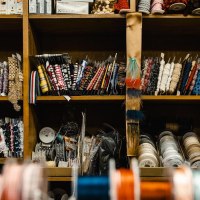 A shelf full of colorful ribbons and spools of thread in a sewing store. Different colors and patterns are neatly sorted., &copy; by Canto
