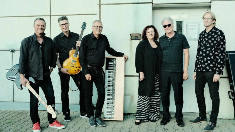 Sechs Personen posieren mit Musikinstrumenten vor einer Wand. Sie tragen &uuml;berwiegend schwarze Kleidung und wirken entspannt und fr&ouml;hlich., &copy; Shady Lane