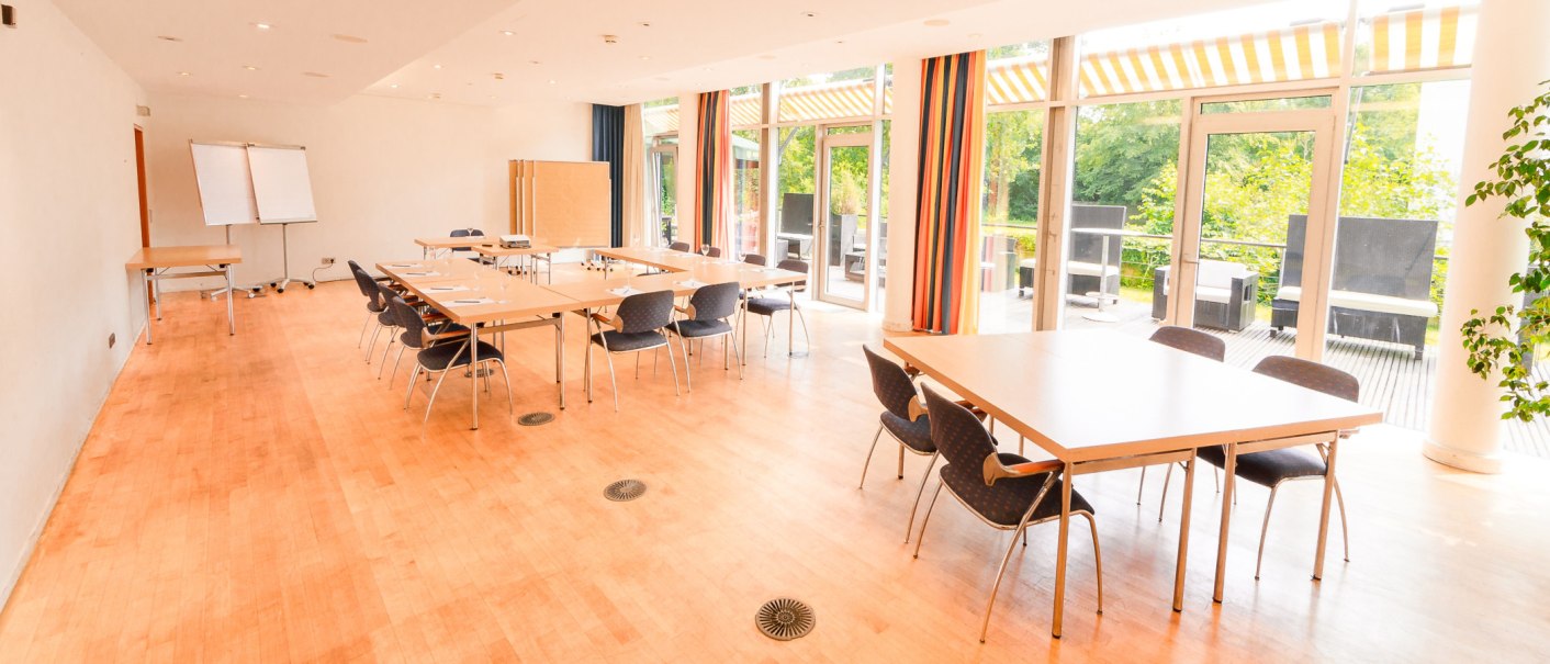 Bright conference room with tables, chairs and flipchart, large windows with a view of the countryside., © PLAZA Hotelgroup GmbH
