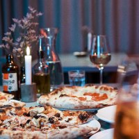 A table in a restaurant with several pizzas, drinks and a burning candle. Glasses and a bottle can be seen in the background., © Italo Disco, Stuttgart A table in a restaurant with several pizzas, drinks and a burning candle. Glasses and a bottle can be seen in the background., © Italo Disco, Stuttgart