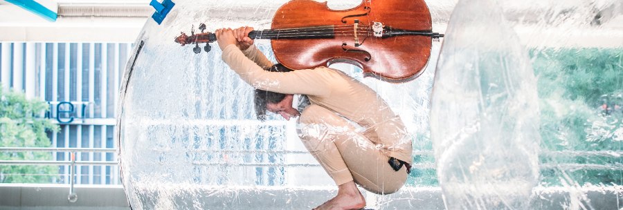 Eine Person sitzt in einer durchsichtigen Kugel und hält ein Cello. Die Szene wirkt künstlerisch und ungewöhnlich., © FREDERIK LAUX PHOTOGRAPHY Eine Person sitzt in einer durchsichtigen Kugel und hält ein Cello. Die Szene wirkt künstlerisch und ungewöhnlich., © FREDERIK LAUX PHOTOGRAPHY