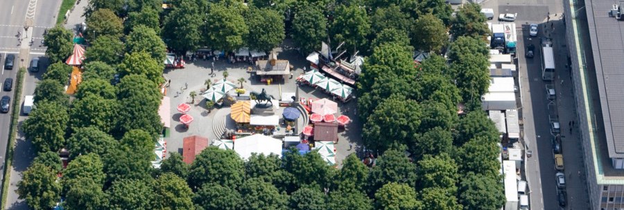 Aerial view of Karlsplatz in Stuttgart. Market stalls and colorful umbrellas are surrounded by trees. An equestrian statue stands in the center., &copy; Stuttgart-Marketing GmbH