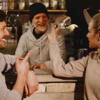 Zwei Personen unterhalten sich l&auml;chelnd mit einem Barista in einem gem&uuml;tlichen Caf&eacute;. Die Atmosph&auml;re ist warm und einladend., &copy; Stuttgart-Marketing GmbH, Alwin Maigler