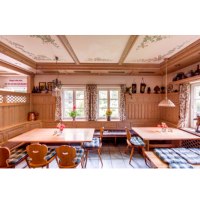 A cozy dining room with wooden furniture, checkered seat cushions and floral curtains. There are floral patterns on the ceiling and ceramics on shelves., © Weingut Karl Wöhrwag A cozy dining room with wooden furniture, checkered seat cushions and floral curtains. There are floral patterns on the ceiling and ceramics on shelves., © Weingut Karl Wöhrwag