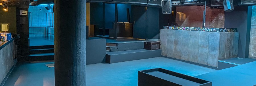 Ein leerer Nachtclub mit blauer Beleuchtung, DJ-Pult und Bar. Der Raum wirkt modern und industriell., &copy; Schr&auml;glage, Stuttgart