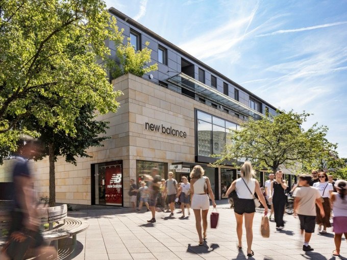 Menschen flanieren vor einem New Balance Geschäft in einem modernen Einkaufszentrum bei sonnigem Wetter., © Schlienz-Tours GmbH & Co.KG Menschen flanieren vor einem New Balance Geschäft in einem modernen Einkaufszentrum bei sonnigem Wetter., © Schlienz-Tours GmbH & Co.KG