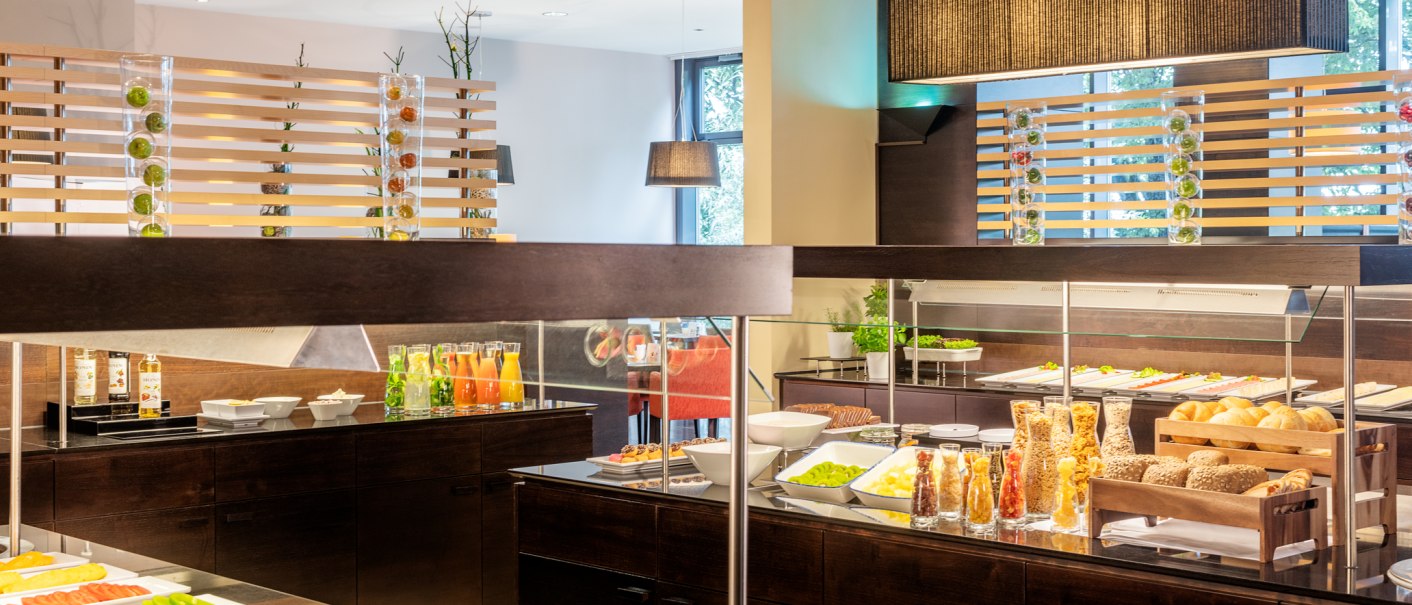 Frühstücksbuffet mit Obst, Gebäck, Müsli und Säften in einem modernen Restaurant., © NH Hotel Stuttgart Airport Frühstücksbuffet mit Obst, Gebäck, Müsli und Säften in einem modernen Restaurant., © NH Hotel Stuttgart Airport