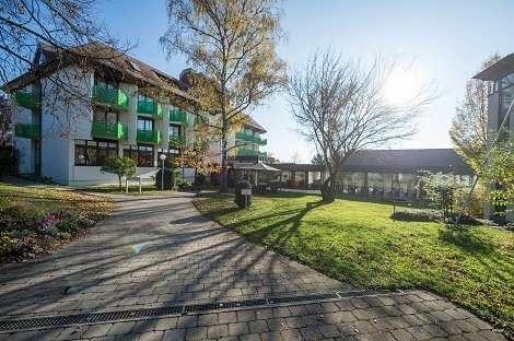 Gebäude mit grünen Balkonen, umgeben von Bäumen und Rasen, bei sonnigem Wetter., © Hotel am Schlossberg Herrenberg