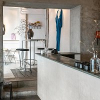 Modern caf&eacute; with minimalist d&eacute;cor, white walls and wooden furniture. A blue piece of clothing hangs on the wall, plants on tables., &copy; SMG Stuttgart Marketing GmbH - Sarah Schmid