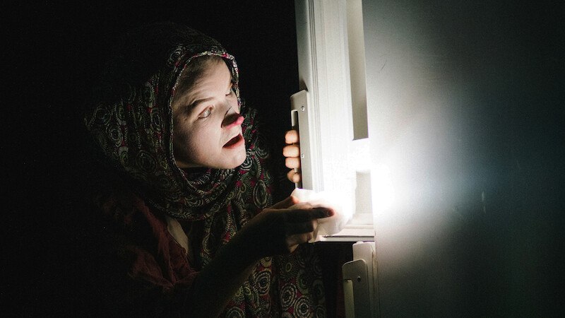 Eine Person mit gemustertem Schal öffnet einen Kühlschrank, aus dem Licht strömt. Die Szene ist dunkel, nur das Kühlschranklicht erhellt das Gesicht., © FITZ Das Theater animierter Formen