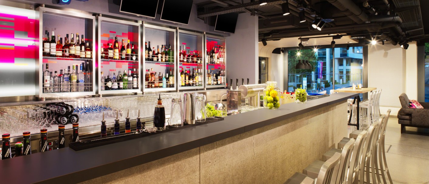 Moderne Bar mit beleuchtetem WXYZ-Schild, gut bestücktem Regal und stilvollen Sitzgelegenheiten. Die Atmosphäre ist einladend und urban., © Aloft Stuttgart Moderne Bar mit beleuchtetem WXYZ-Schild, gut bestücktem Regal und stilvollen Sitzgelegenheiten. Die Atmosphäre ist einladend und urban., © Aloft Stuttgart