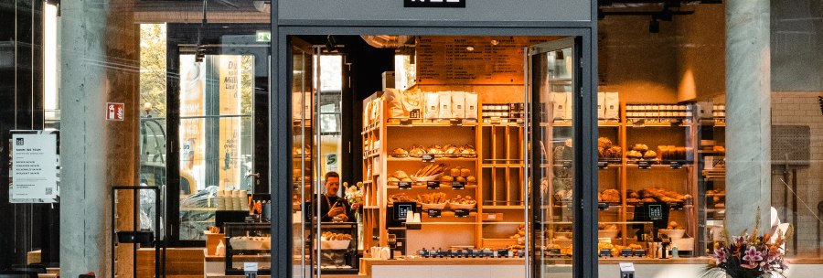 Entrance to a bakery with a glass front. Shelves with baked goods can be seen inside. 'Time for bread' is written above the door., &copy; Zeit f&uuml;r Brot Stuttgart