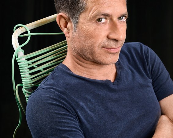 A man in a blue T-shirt sits on a green chair and looks confidently into the camera., &copy; Theaterhaus Stuttgart e.V.