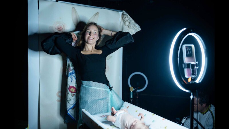 Eine Frau posiert vor einem Hintergrund mit Hasenohren, w&auml;hrend ein Baby auf einem Tisch liegt. Ein Ringlicht und ein Smartphone sind im Vordergrund., &copy; FITZ Das Theater animierter Formen