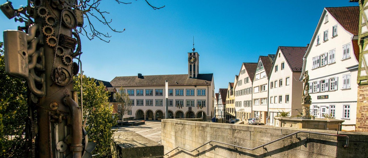 The market square in Böblingen shows historic buildings and an artistic sculpture in the foreground under a clear blue sky., © Stuttgart-Marketing GmbH, Sarah Schmid