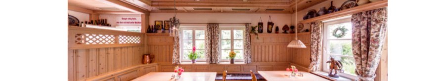 A cozy dining room with wooden furniture, checkered seat cushions and floral curtains. There are floral patterns on the ceiling and ceramics on shelves., © Weingut Karl Wöhrwag A cozy dining room with wooden furniture, checkered seat cushions and floral curtains. There are floral patterns on the ceiling and ceramics on shelves., © Weingut Karl Wöhrwag