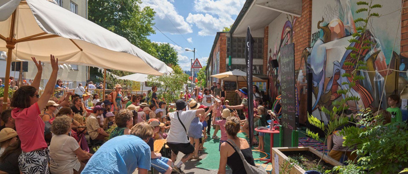 Fröhliche Menschen genießen ein Straßenkunstfestival mit bunten Wandgemälden und Sonnenschirmen. Eine lebendige Atmosphäre bei sonnigem Wetter., © Ronny Schoenebaum Fröhliche Menschen genießen ein Straßenkunstfestival mit bunten Wandgemälden und Sonnenschirmen. Eine lebendige Atmosphäre bei sonnigem Wetter., © Ronny Schoenebaum
