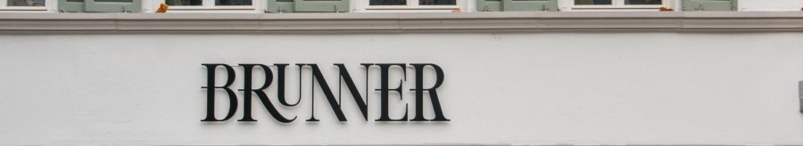 Lettering on the facade of the Brunner restaurant with serifs. Above it, lattice windows with green shutters., &copy; SMG, Sarah Schmid