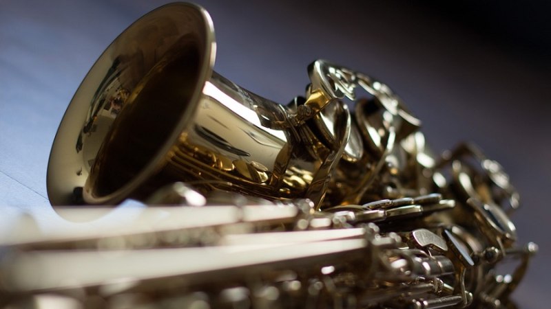 Nahaufnahme eines goldenen Saxophons, das auf einem Tisch liegt. Der Fokus liegt auf dem Schallbecher und den Klappen., © Pixabay Nahaufnahme eines goldenen Saxophons, das auf einem Tisch liegt. Der Fokus liegt auf dem Schallbecher und den Klappen., © Pixabay