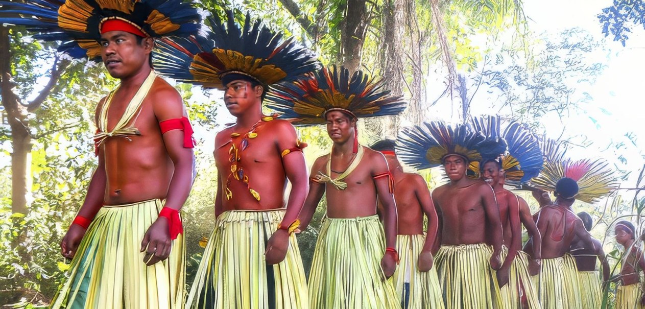Men in traditional clothing with large, colorful headdresses march through a forest. They wear skirts made from plant fibers., © Linden-Museum Stuttgart Men in traditional clothing with large, colorful headdresses march through a forest. They wear skirts made from plant fibers., © Linden-Museum Stuttgart